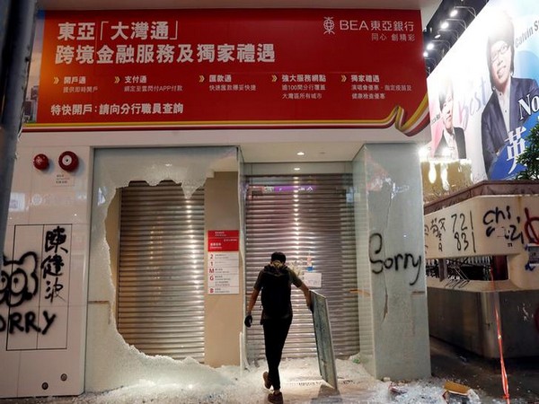 A man stands in front of the Bank of East Asia that was vandalised by anti-government protesters in Hong Kong on October 20