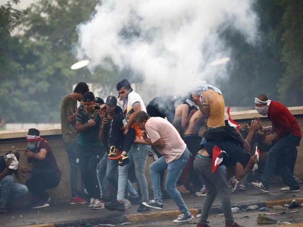 Demonstrators disperse as Iraqi security forces use tear gas during a protest in Baghdad on Friday
