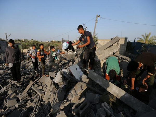 Palestinians collect belongings from a house destroyed in an Israeli air strike in the southern Gaza Strip on Thursday