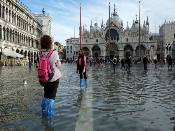 Tourists pose for photographs in St. Mark's Square after days of severe flooding in Venice