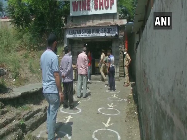 People standing in a queue, adhering to social distancing norms, outside a liquor shop in Jammu.
