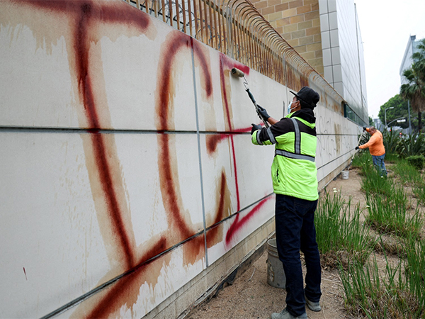 Workers clean up graffiti on a detention centre building, after days of protests against federal immigration sweeps and the deployment of California National Guard and US Marines, in Los Angeles, California on June 11, 2025. (Photo/Reuters)