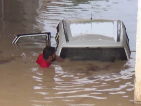 Locals carrying out rescue work in car stuck at underpass in Jhunjhunu. Photo/ANI