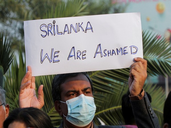 A man along with others carries a sign, condemning the lynching of the Sri Lankan manager of a garment factory in Pakistan. (Image credit: Reuters)