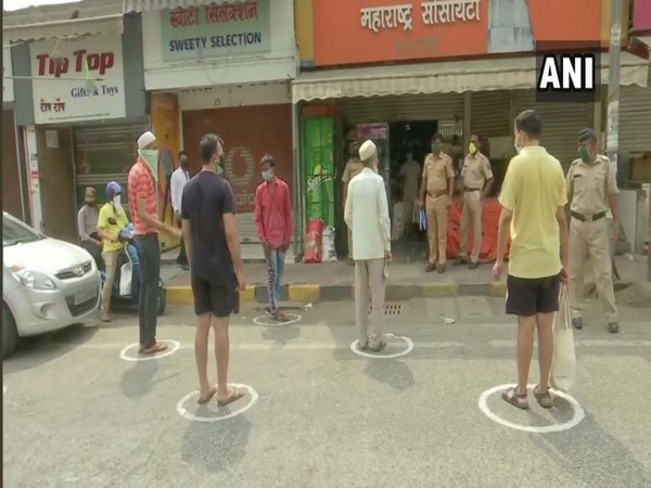 People standing in separate circles marked with chalk while collecting basic supplies from a grocery shop at Andheri East on Wednesday. Photo/ANI