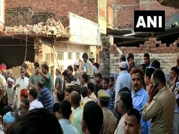 Locals gather at the spot where a house collapsed following a cylinder blast in Mau, Uttar Pradesh on Monday