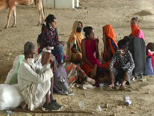 A family waiting for a bus back home at Gazipur, Delhi on Monday. [Photo/ANI]