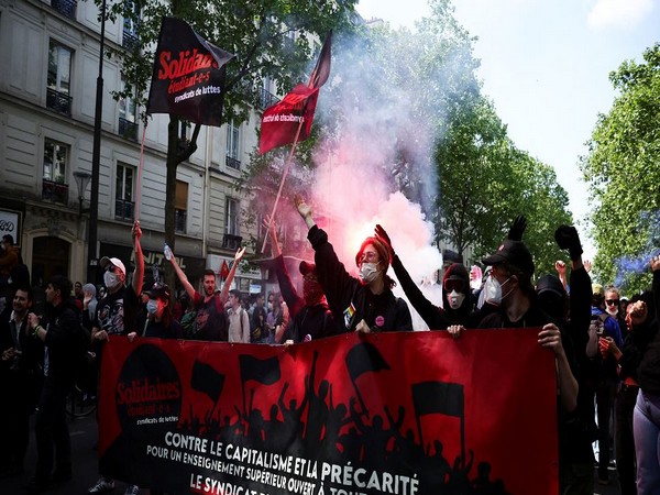Masked protesters walk with a banner during the traditional May Day labour union march in Paris, France, May 1, 2022 (Photo Credit: Reuters)