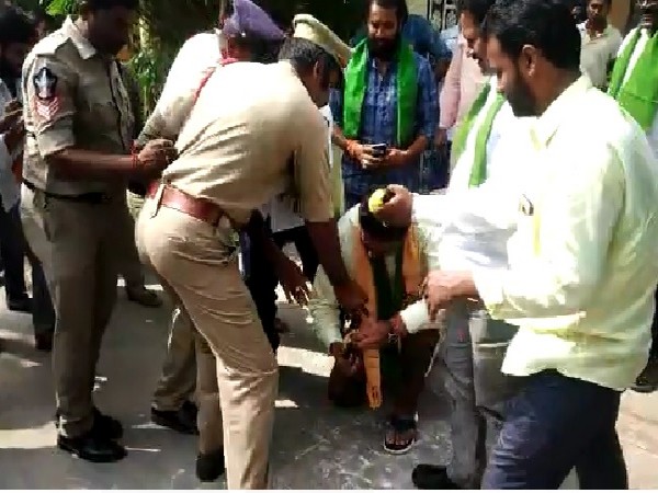 Former TDP MLA Bode Prasad tried to polish the shoes of a police officer in Penamaluru, Andhra Pradesh on Tuesday.  Photo/ANI