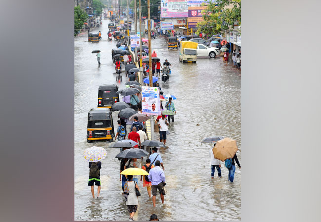 People walk on a flooded road after heavy rainfall at Nala Sopara in Mumbai [Photo/ANI]