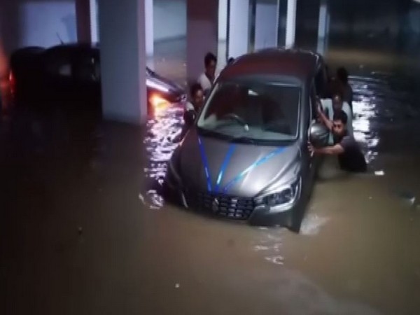 People moving their vehicle from the waterlogged parking lot of some area in Hyderabad after heavy rains lashed the area on Thursday. Photo/ANI