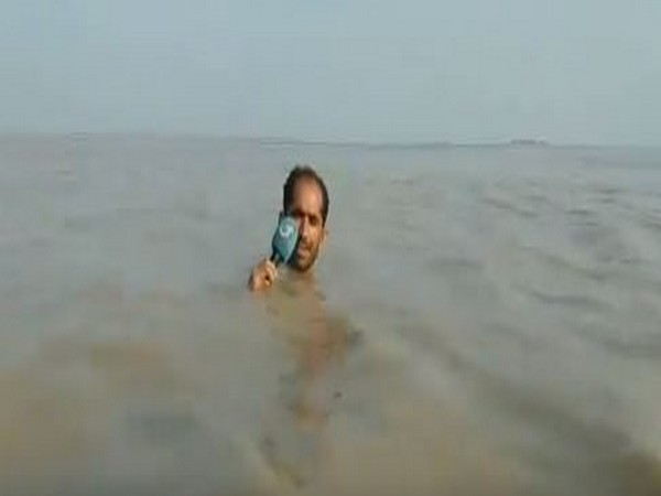 Journalist Azadar Hussain, standing neck-deep in water to report on floods. (Photo courtesy: Salman Qureshi twitter handle)