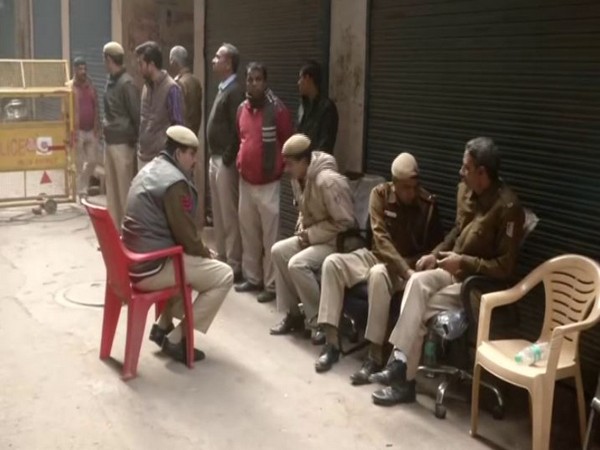 Police sitting outside the shops in Filmistan area  on Tuesday [Photo/ANI]