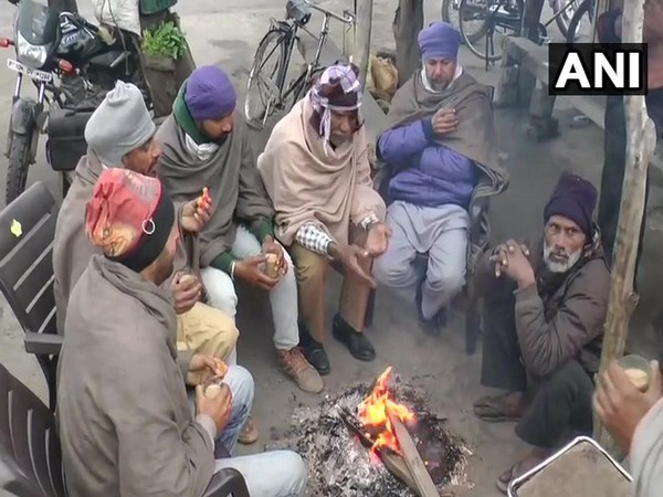 Visual of people sitting around bonfire in Ludhiana. Photo/ANI