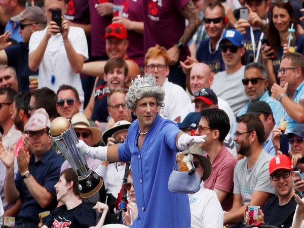 A fan dressed as Queen Elizabeth holding a replica of World Cup trophy