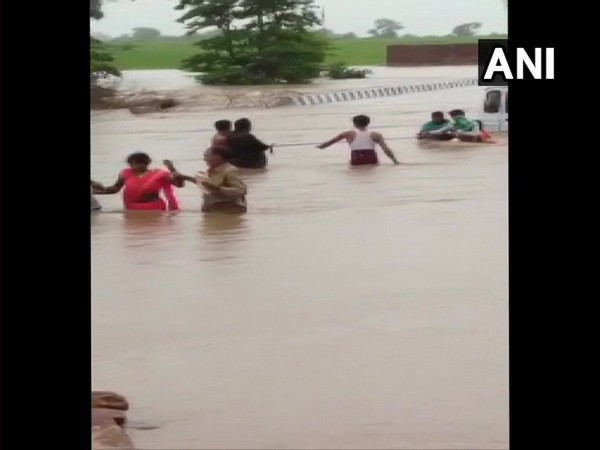 locals helps rescue few stranded people at a flooded bridge in Sagar District