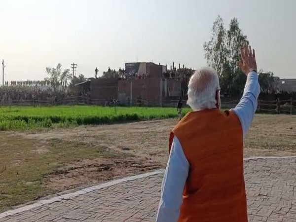 Prime Minister Narendra Modi waving at people, waiting to welcome him in Unnao.