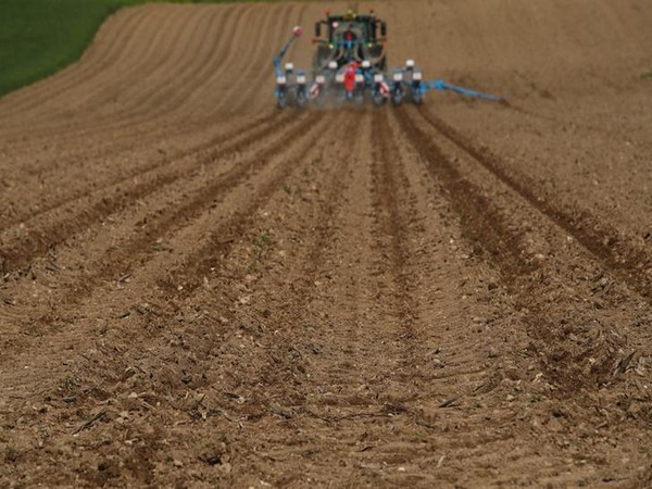 A tractor sows seeds in a field in Lavigny,