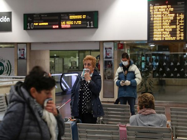 Women cover their mouths as they wait in the lobby of Chamartin train station