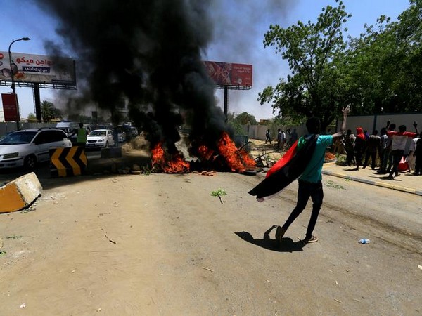 A Sudanese protester gestures as they burn tyres and barricade the road leading to al-Mek Nimir Bridge crossing over Blue Nile; that links Khartoum North and Khartoum, in Sudan on Monday