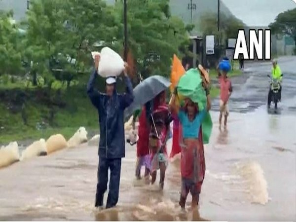 Vsual of people crossing a flooded road in Nashik (Photo/ANI)
