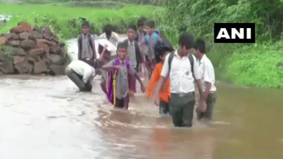 Students crossing the 3-foot-deep flooded road to reach school in Thane in Maharashtra. Photo/ANI