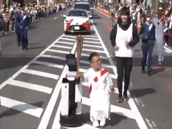 A robot helping to carry the Olympic torch (Image: #Tokyo 2020's Twitter)