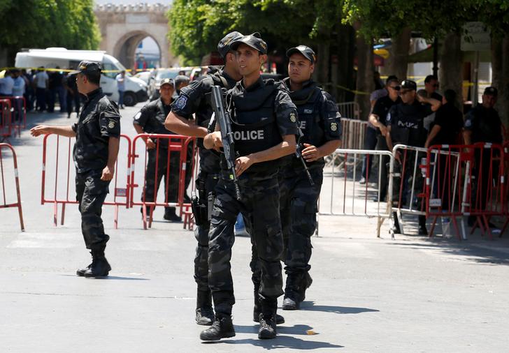 Police officers stand guard near the site of a suicide bombing attack in downtown Tunis on Thursday