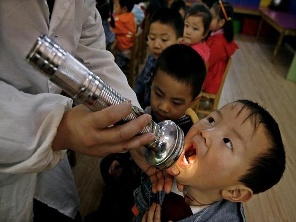 A boy has his mouth checked as part of measures to prevent the hand, foot and mouth disease (HFMD) at a kindergarten in Wuhan