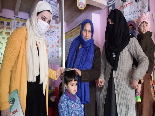 Anganwadi workers measuring child's height via stadiometer under ICDS scheme in Jammu and Kashmir's Pulwama on Wednesday. (Photo/ANI)