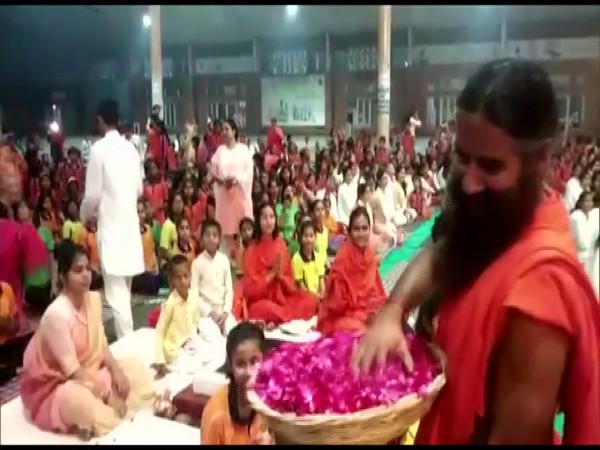 Ramdev celebrated Holi in Haridwar while throwing flower petals on those gathered at Patanjali Yogpeeth. (Photo/ANI)