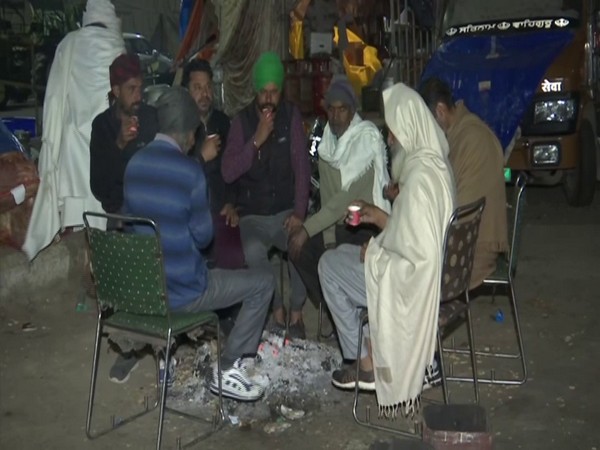 farmers at the Ghazipur border sitting in front of fire (Photo/ANI)