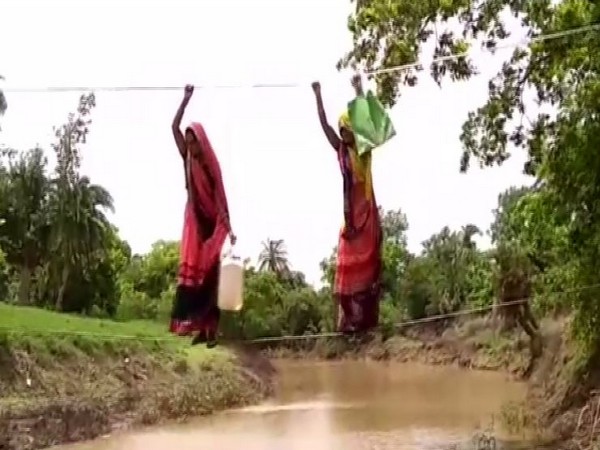 Women crossing the river stream through the make-shift rope bridge (Photo/ANI)