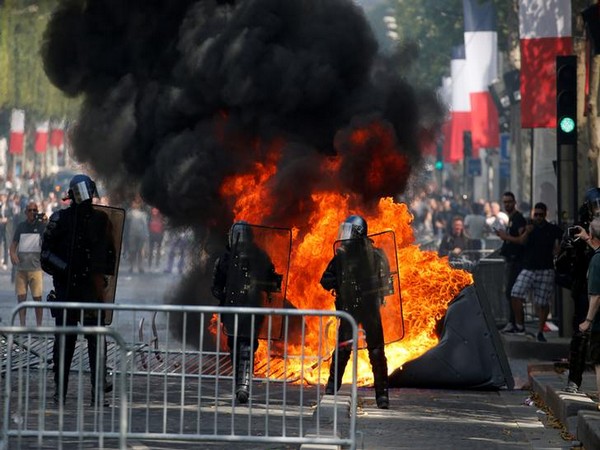 Law enforcement officials stand in front of a burning portable toilet at the Champs Elysees in Paris on Sunday (Photo/Reuters)